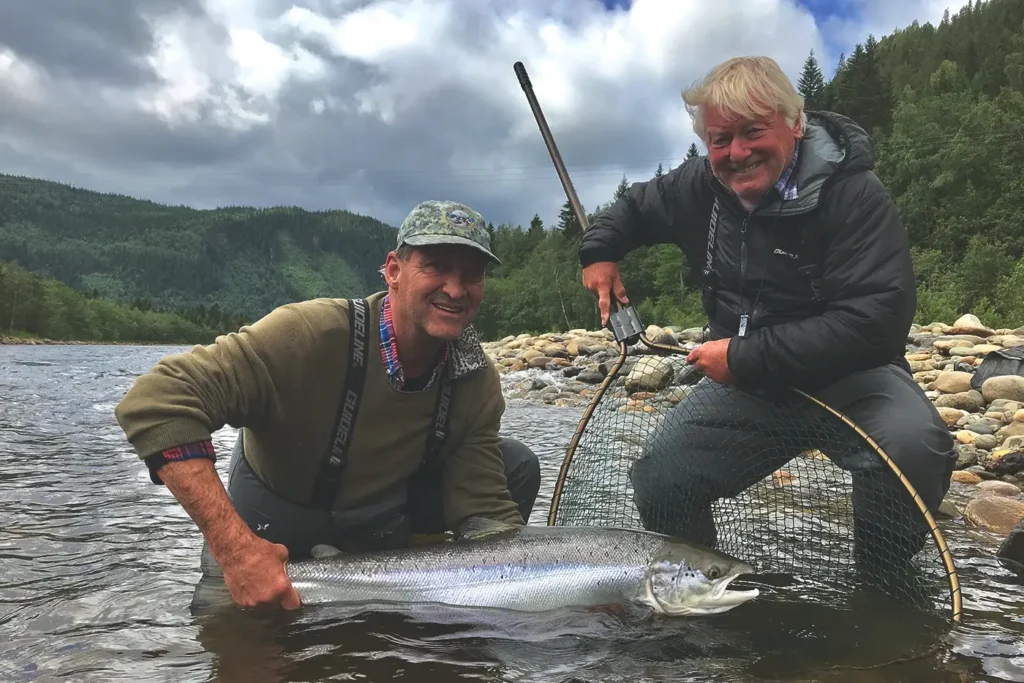 Two men presenting a fish in a river.