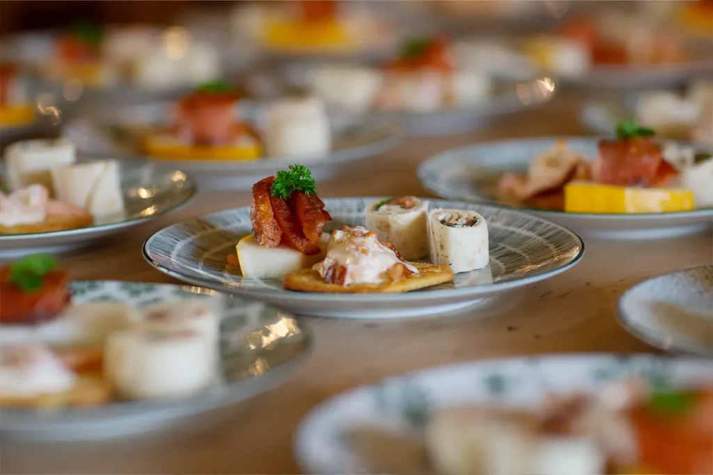 At a festive Julemesse, plates with assorted appetizers delight the senses, featuring crackers topped with bacon and parsley, tortilla wraps, and diced cheese. Each dish reflects the thoughtful preparation synonymous with Winsnes gatherings.